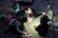 Otroci berejo ob soju baterijske svetilke.