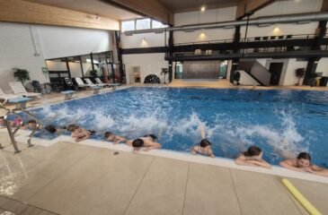 Otroci čofotajo ob robu bazena.